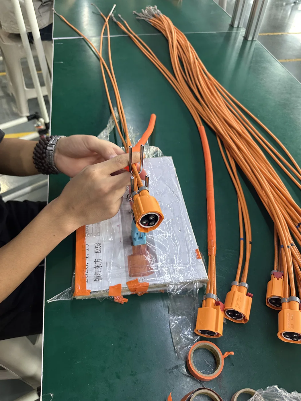 Close-up of manual terminal processing on an orange high-voltage cable