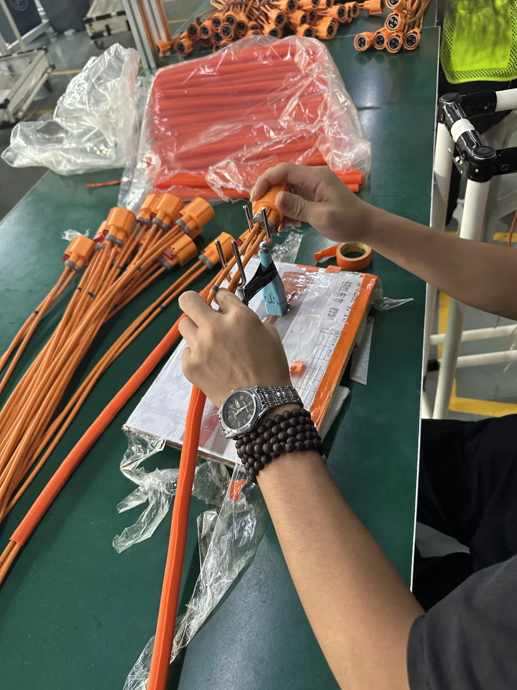 完成したケーブルセットにコネクタ組立を完了する作業者
