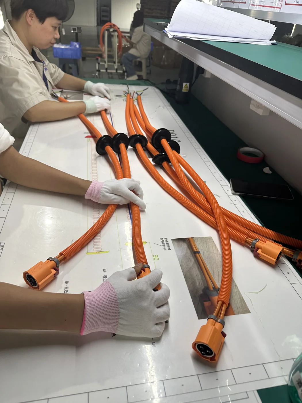 Operator preparing a set of orange high-voltage wiring harnesses