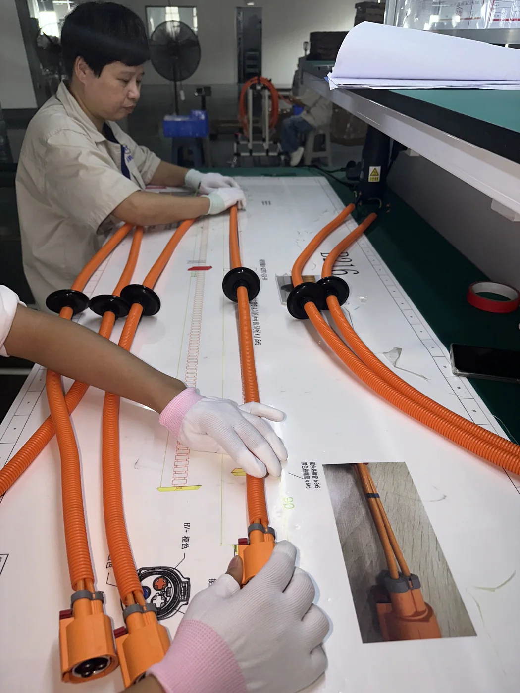 作業指示書に合わせて高電圧ワイヤーハーネス分岐を整列する作業者