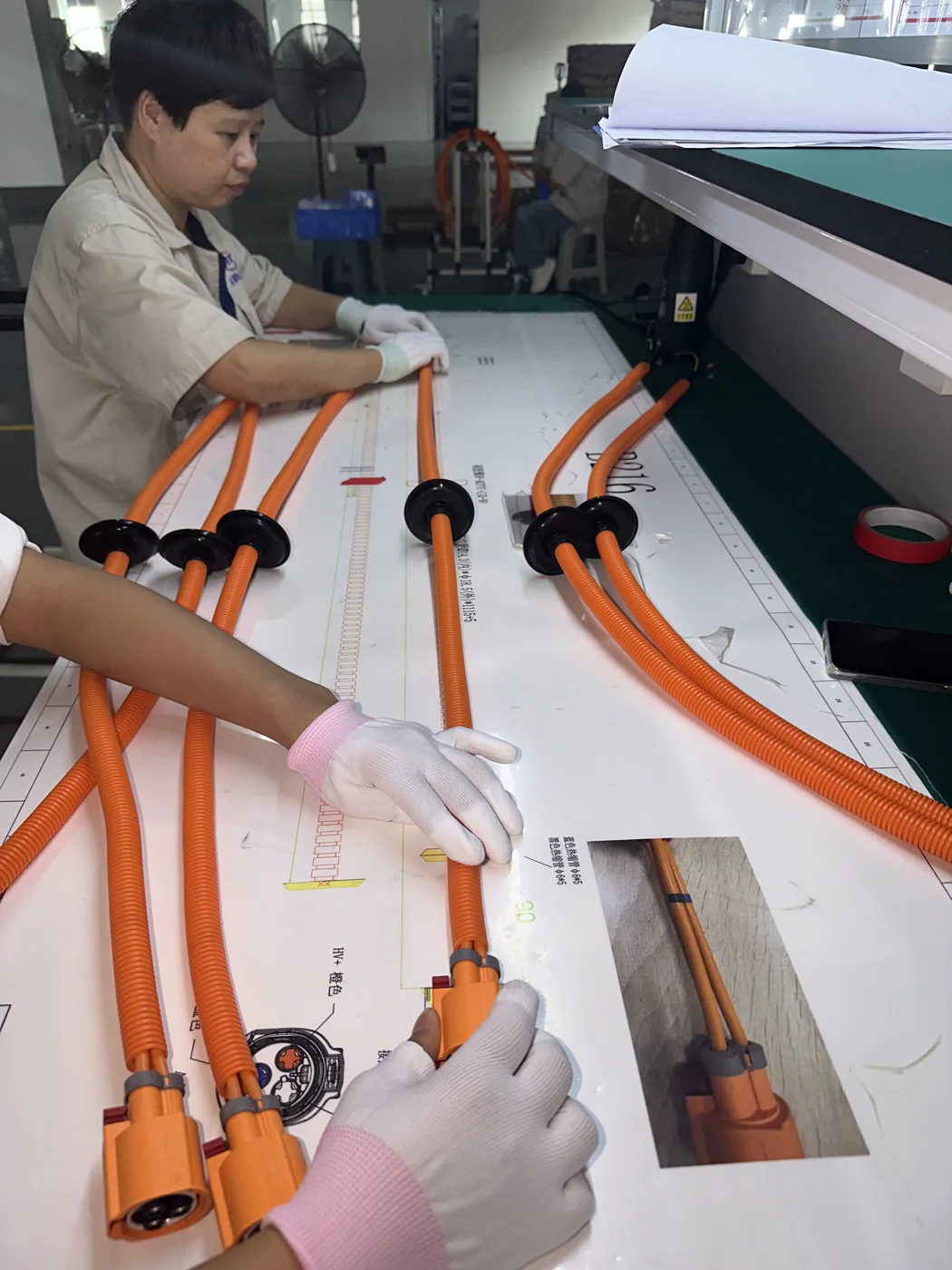 Operator checking high-voltage harness routing during assembly